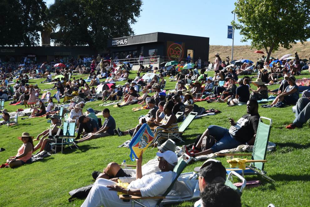People sit on picnic blankets and low chairs while enjoying the Concord Jazz Fest