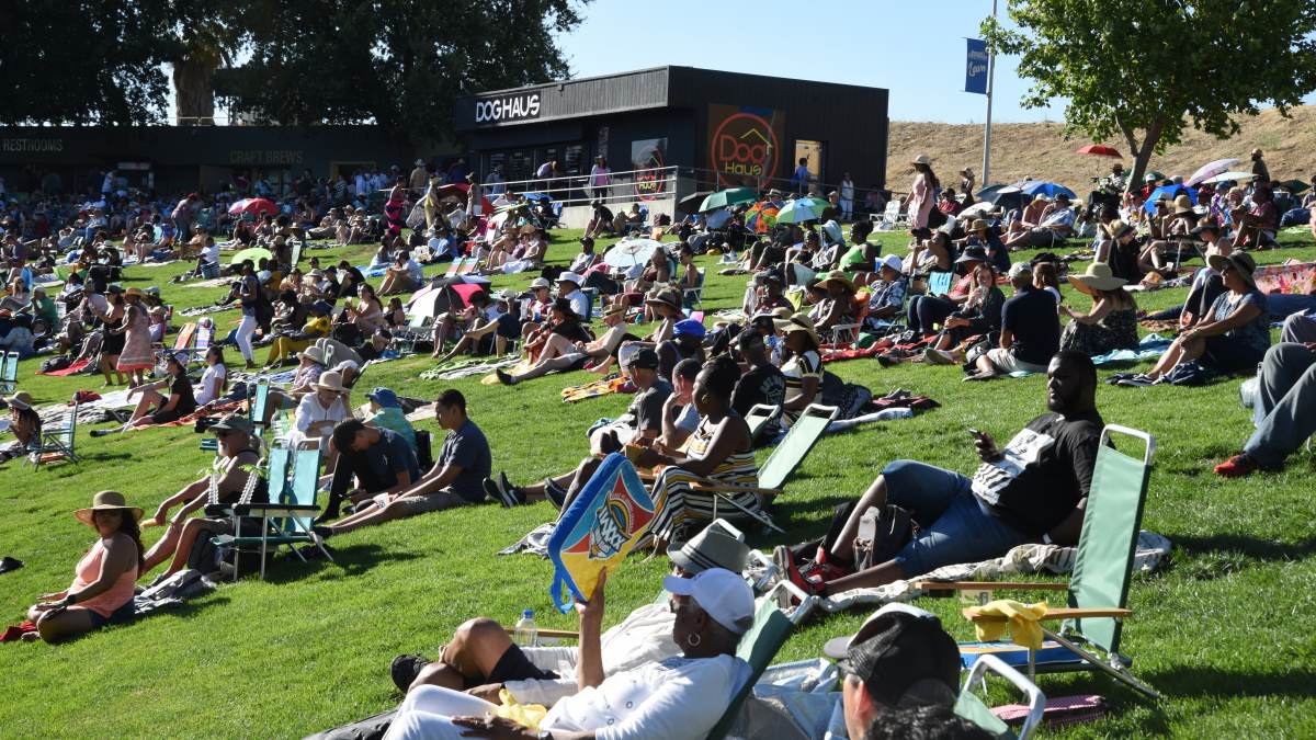 People sit on picnic blankets and low chairs while enjoying the Concord Jazz Fest