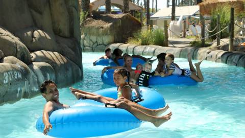 Family floating on blue tubes down a lazy river at Hurricane Harbor waterpark concord ca