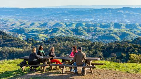 people sitting at tables on a hillside