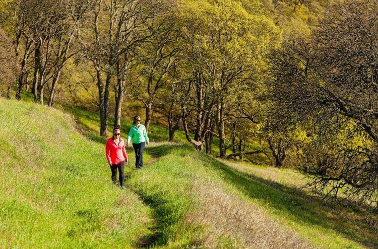 two women hiking up grassy hill