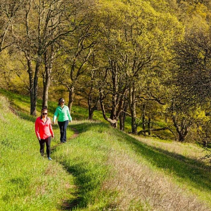 two women hiking up grassy hill