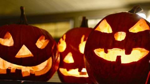 A series of three jack-o'-lanterns lit up by candles in the dark of the night for Halloween in Concord, CA.
