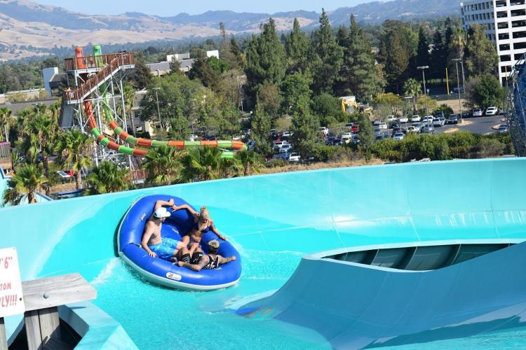 Family rides an inner tube down the slide at a water park