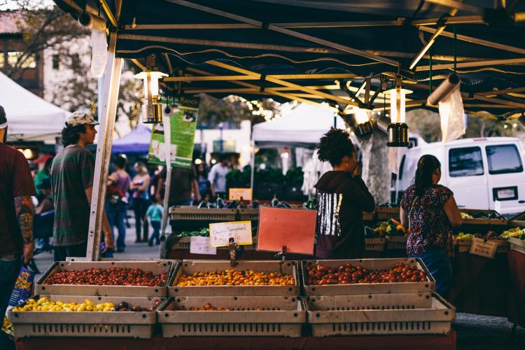 People walking around farmer's market booths and looking at fresh vegetables at Todos Santos Farmers Market in Concord CA
